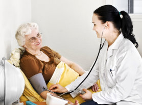 elderly woman in bed having her blood pressure checked